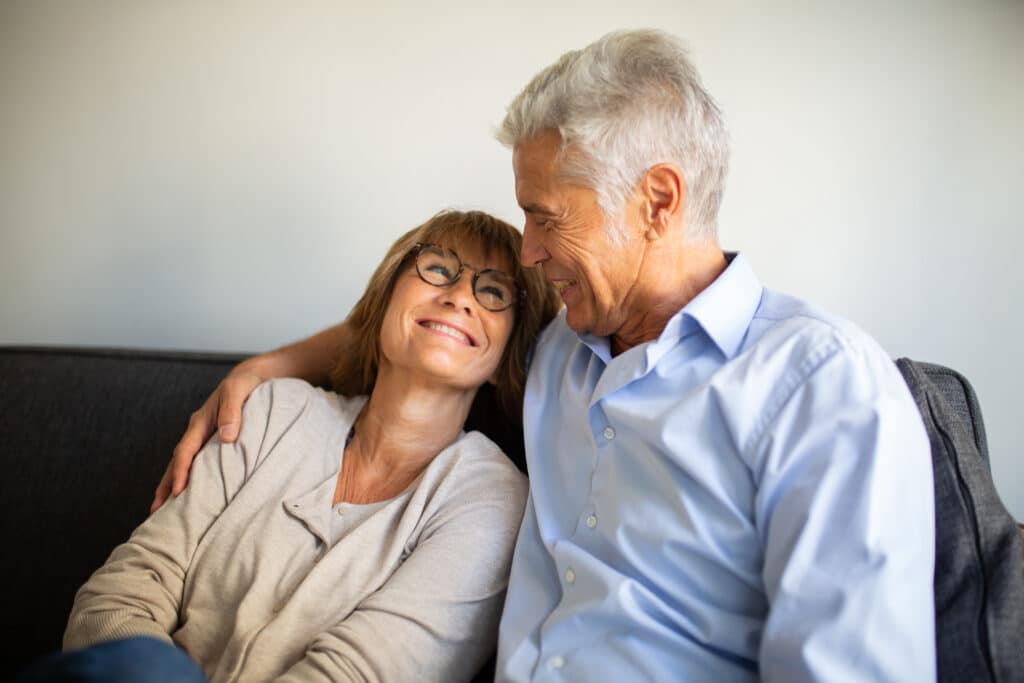 smiling older man and woman sitting on sofa together